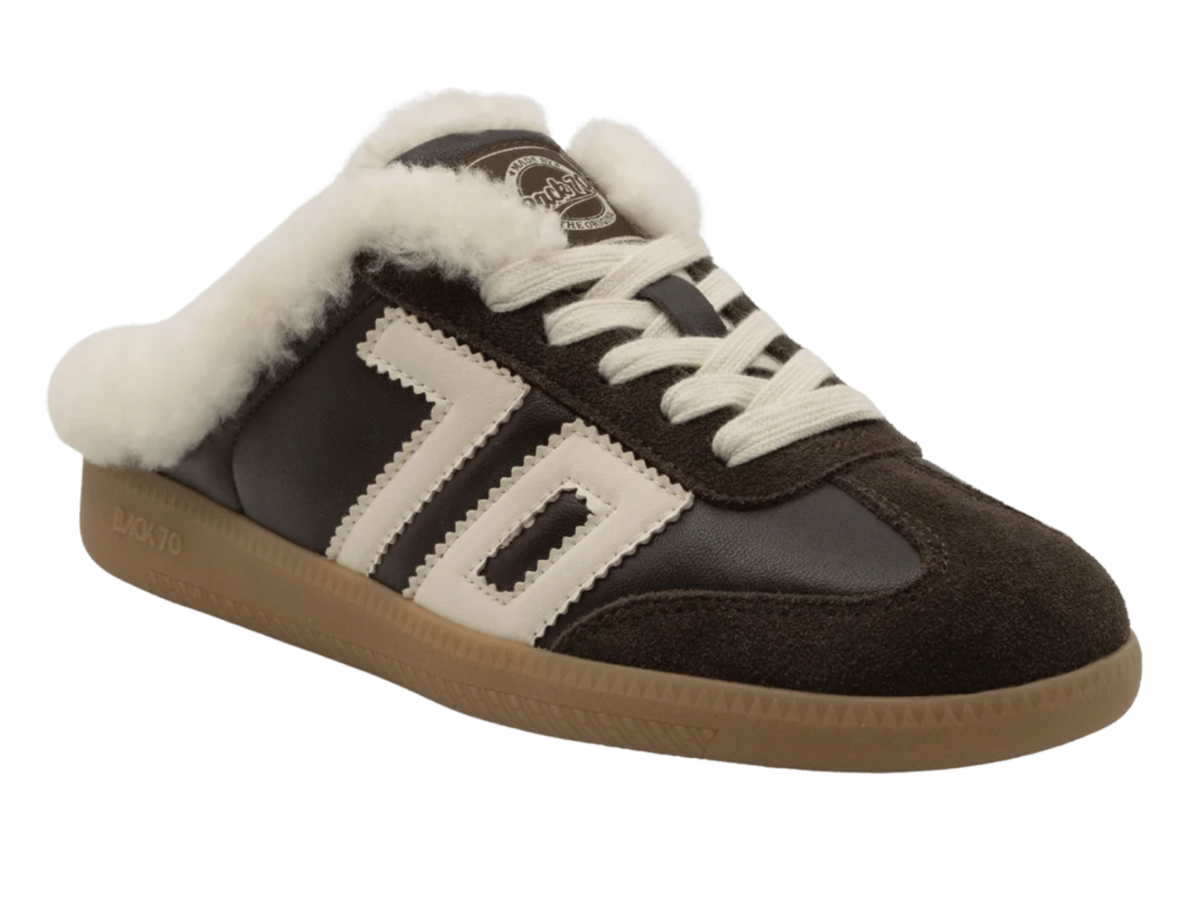 A dark brown suede and leather slip-on sneaker with a thick white faux-fur collar, white laces, and a tan gum sole, shown on a plain white background.
