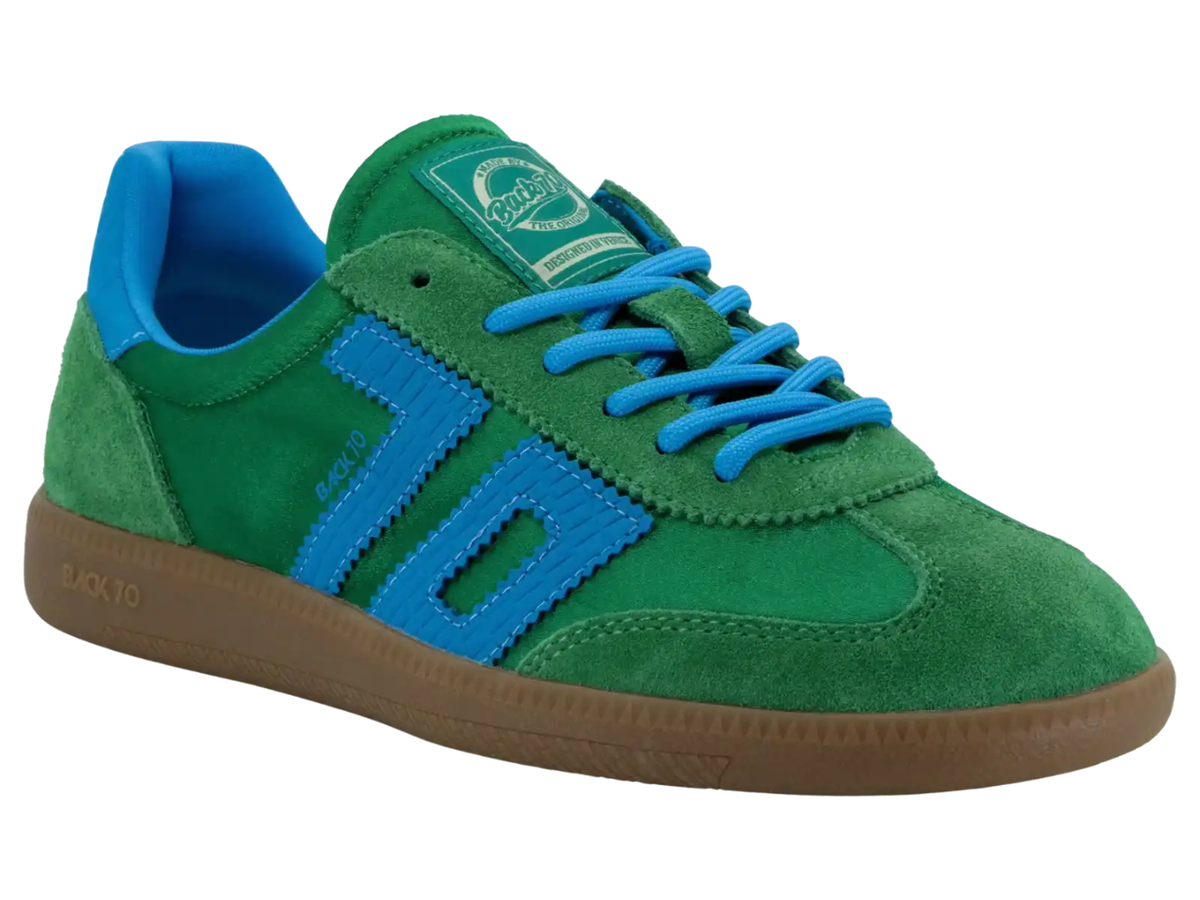 A green suede sneaker with bright blue laces, a blue side stripe, and a blue collar lining, featuring a brown gum sole.