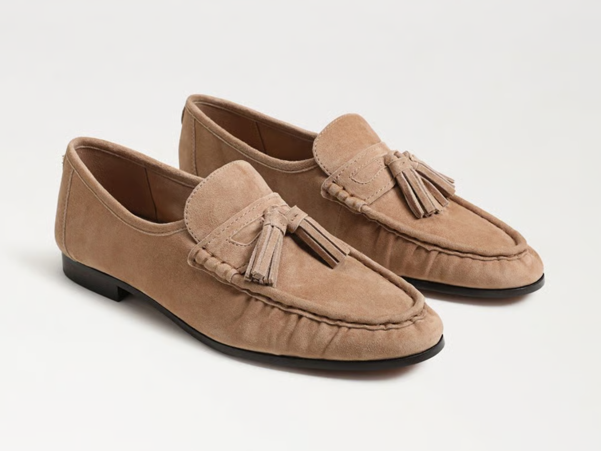 A pair of taupe suede moccasin loafers with tassel straps, displayed on a clean white background.