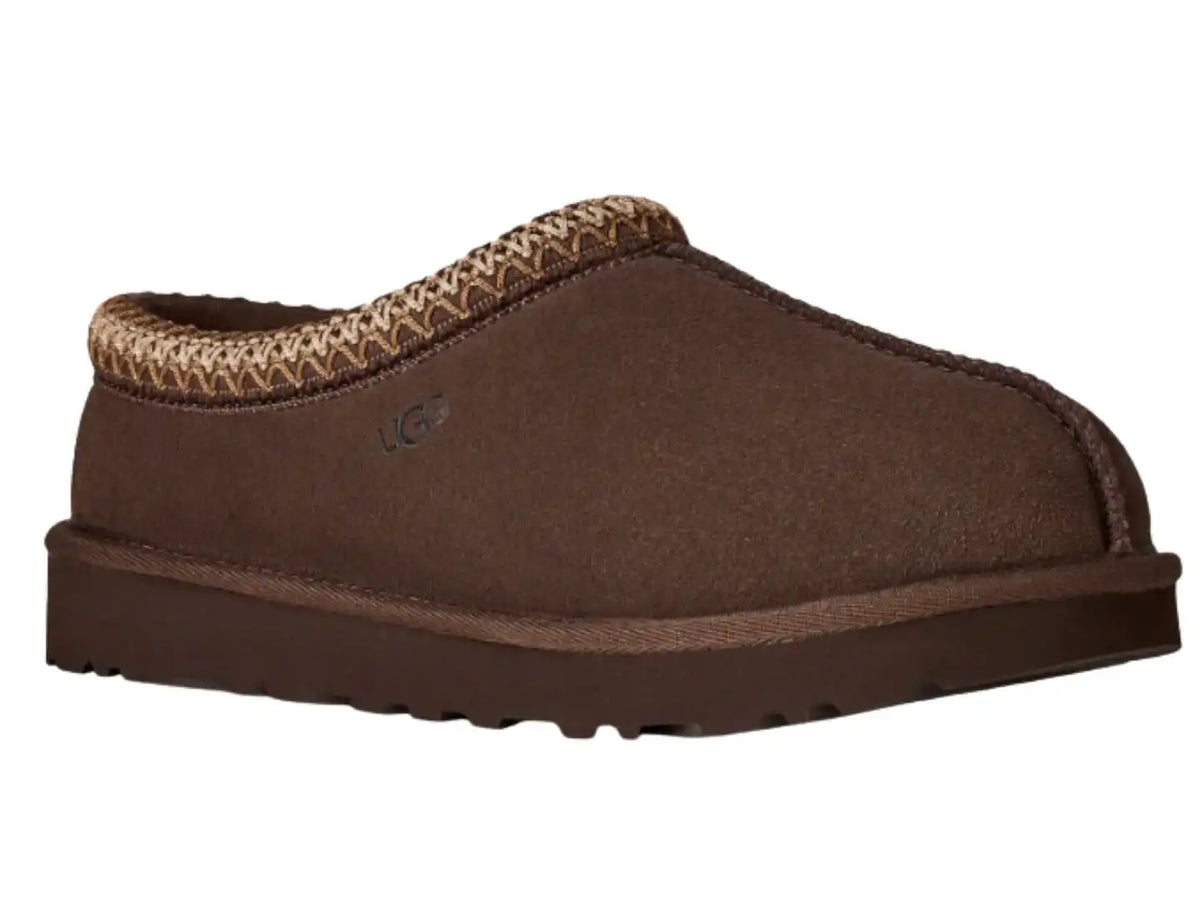 A brown suede slip-on mule shoe with a patterned knit collar and a dark brown sole, shown on a plain white background. A small UGG logo is visible on the side.