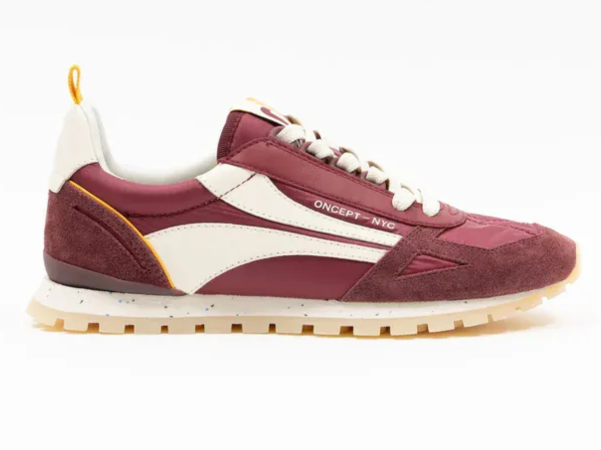 A burgundy and cream sneaker with a textured cream midsole and a small yellow pull tab, shown from the side on a white background.
