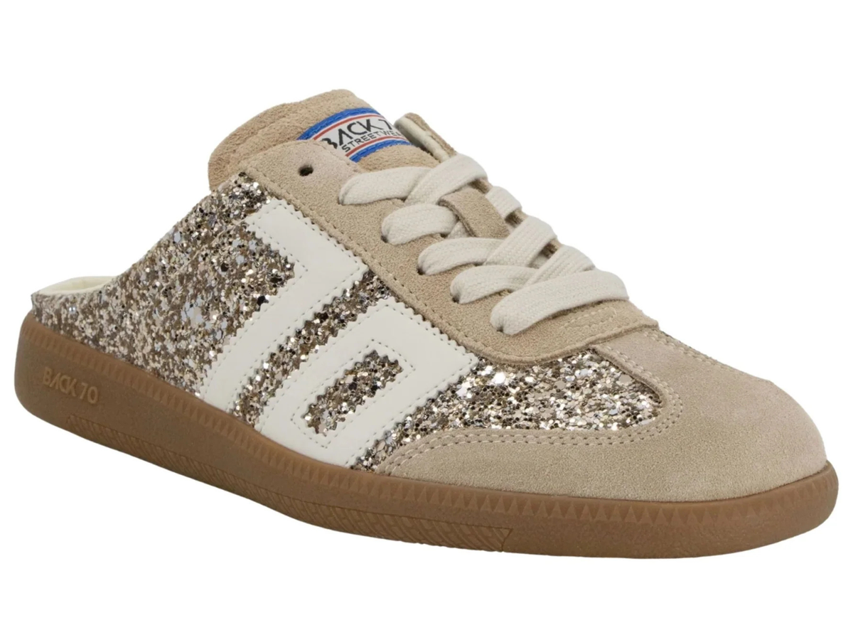 A beige suede and white leather sneaker-style mule with chunky glittery silver side stripes, white laces, and a brown gum sole.
