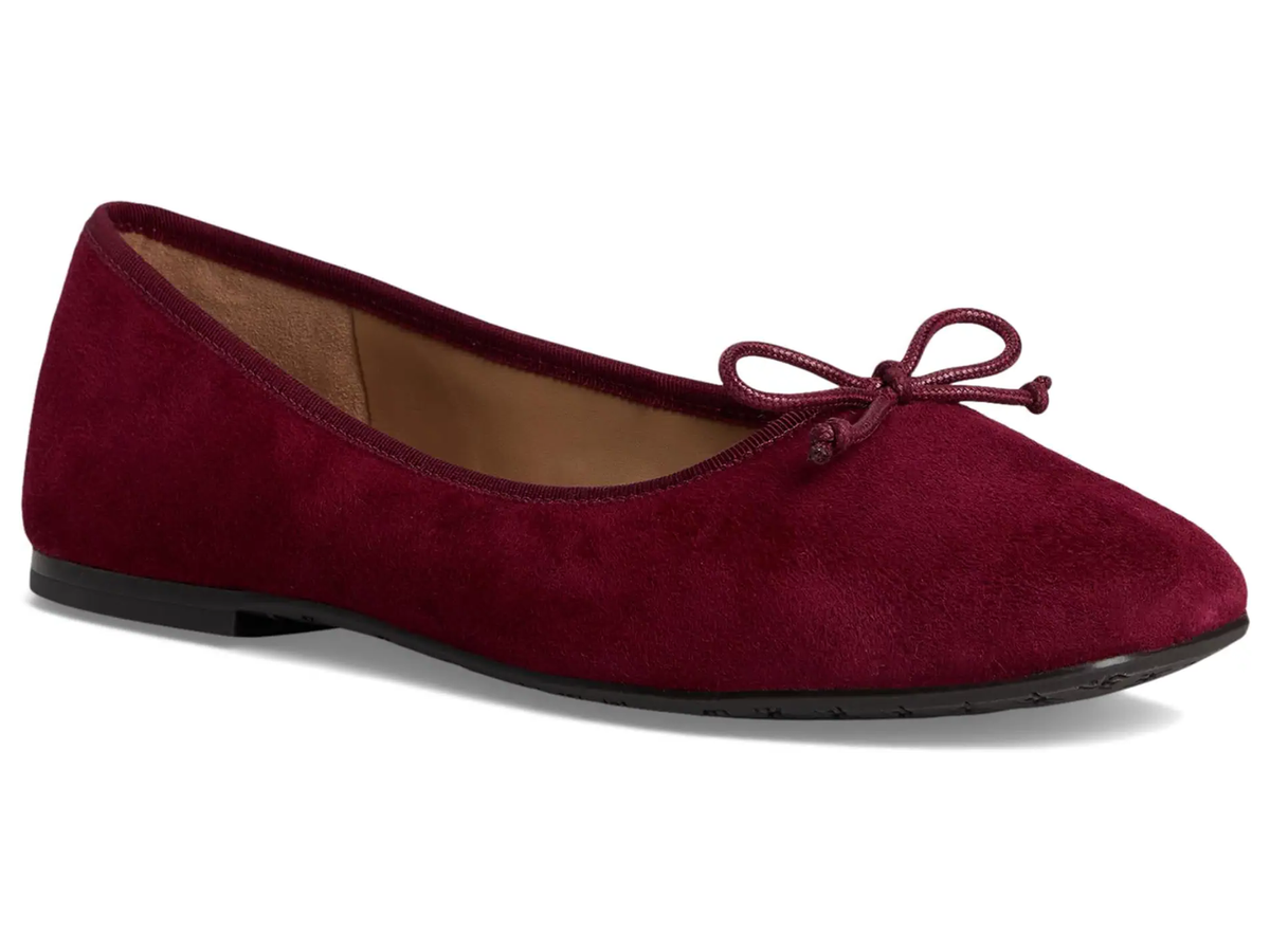 A single burgundy suede ballet flat shoe with a matching fabric bow on the toe, shown from a side profile against a white background.